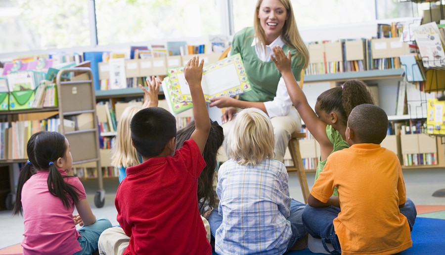 Kindergarten teacher reading to children in library