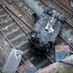 Súlyos autóbaleset, egy autó áttörte a korlátot és a sínekre zuhant Angliában, Salfordban