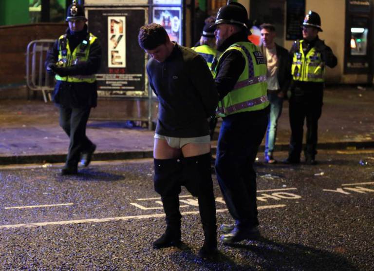 Pictured: A man whose trousers are falling down is detained by police officers Friday 01 January 2016  Re: New Year revellers in Wind Street, Swansea, south Wales.