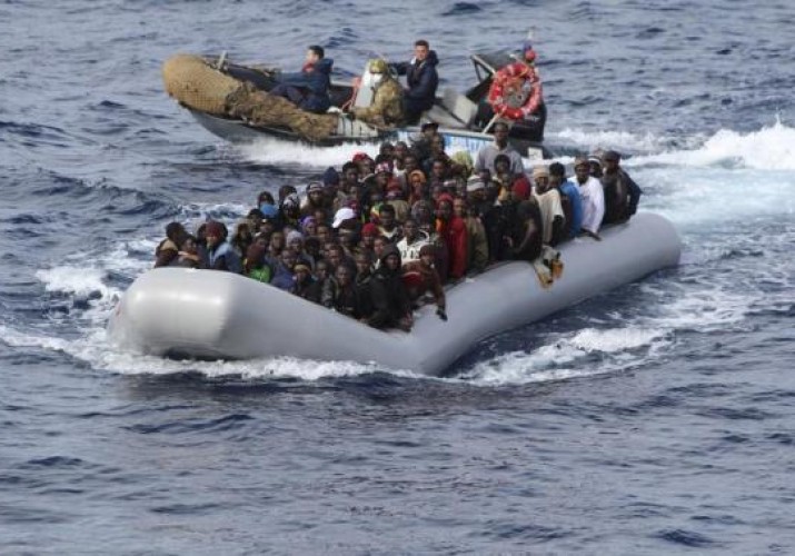 Migrants sit in a boat during a rescue operation by Italian navy off the coast of the south of the Italian island of Sicily