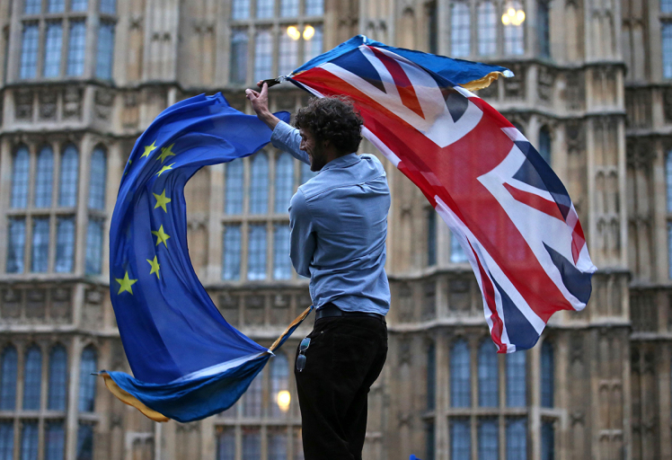 A man waves both a Union flag and a European flag together on College Green outside The Houses of Parliament at an anti-Brexit protest in central London on June 28, 2016. EU leaders attempted to rescue the European project and Prime Minister David Cameron sought to calm fears over Britain's vote to leave the bloc as ratings agencies downgraded the country. Britain has been pitched into uncertainty by the June 23 referendum result, with Cameron announcing his resignation, the economy facing a string of shocks and Scotland making a fresh threat to break away. / AFP / JUSTIN TALLIS (Photo credit should read JUSTIN TALLIS/AFP/Getty Images)